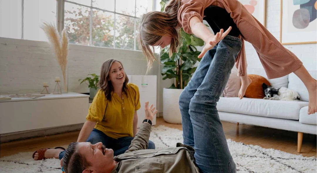 A family playing on the rug in a sunlit living room